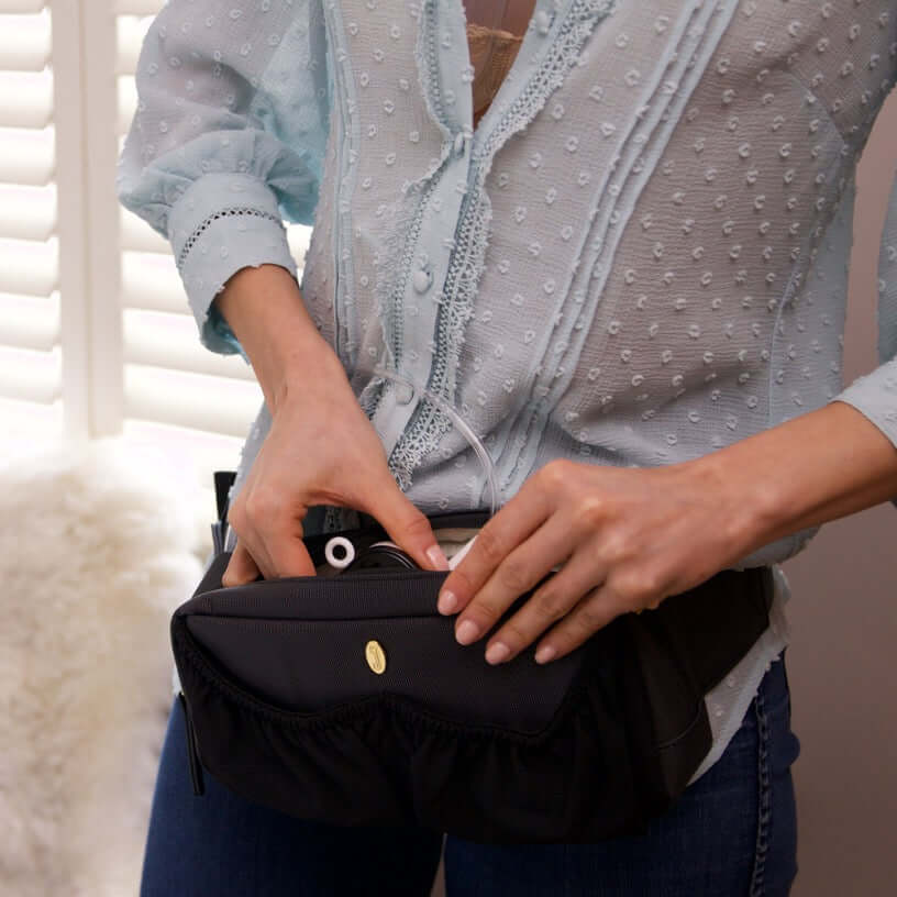 mom placing the pump motor on the designated compartment of pump-a-porter mini wearable breast pump bag