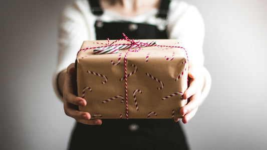 Hands holding out a gift wrapped in brown paper