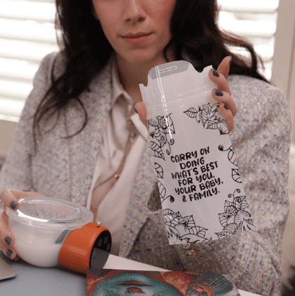 mom holding the breast milk bag with opened lid on one hand while holding the pump-a-wear filled with milk on the other hand