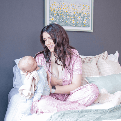 mom comfortably wearing milk-a-save milk collector shells while burping her baby