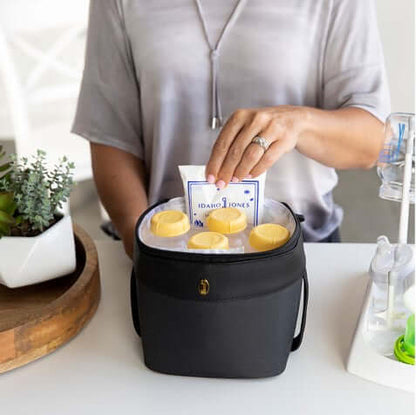 mom placing the jamie reusable ice packs in the designated pocket of roxwell cooler bag with bottles filled of pumped milks