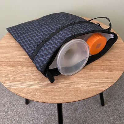 robin wet dry bag for breast pump parts on a table with flanges and milk bottles